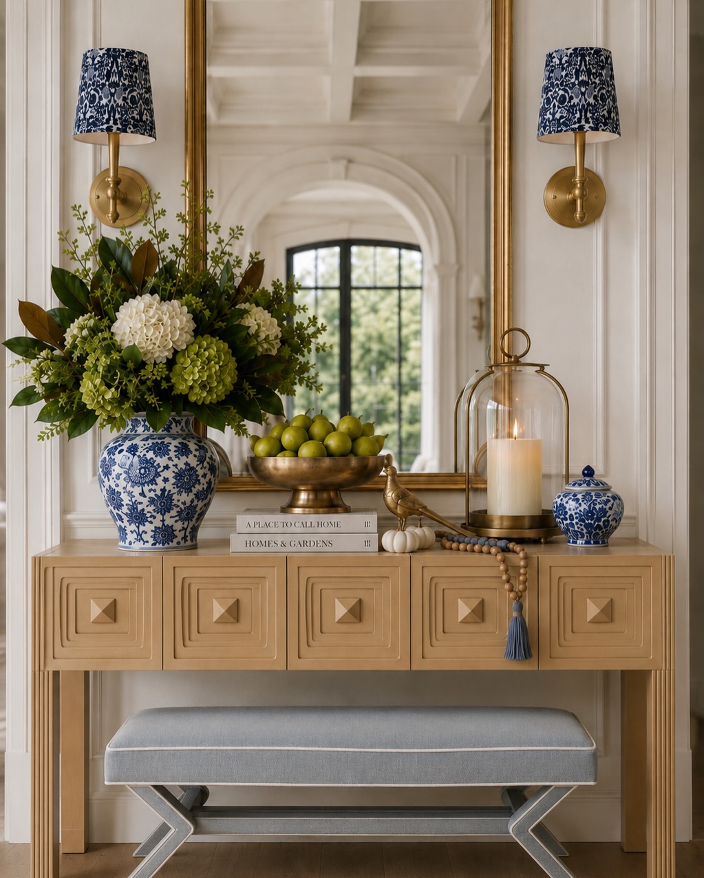 Blue and white seasonal styling with a warm wood console, patterned sconces, and a botanical arrangement.